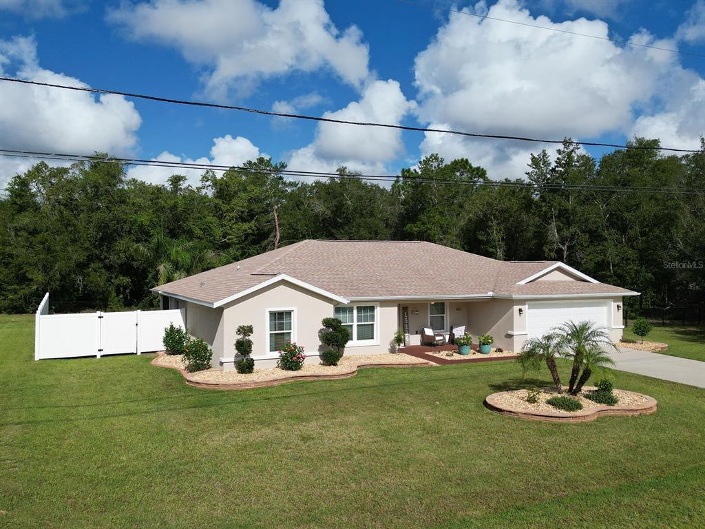 A single-story house with a beige exterior, a tan roof, and a white fence — 15136 SE 93RD AVENUE, SUMMERFIELD, FL