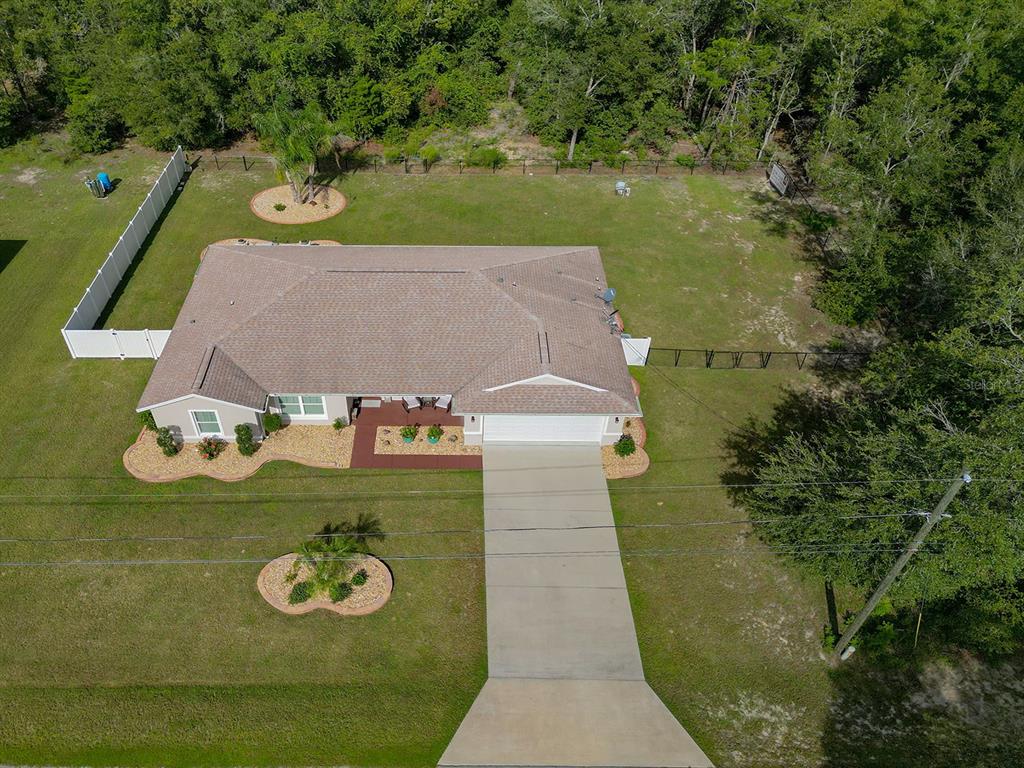An aerial view shows a single-story house with a brown roof and a concrete driveway — 15136 SE 93RD AVENUE, SUMMERFIELD, FL