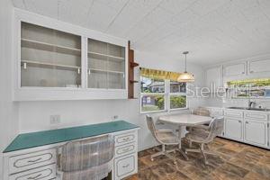 A kitchen features white cabinetry, a built-in desk, a small dining table, and tile flooring — 3896 PICCIOLA UNIT 224, FRUITLAND PARK, FL