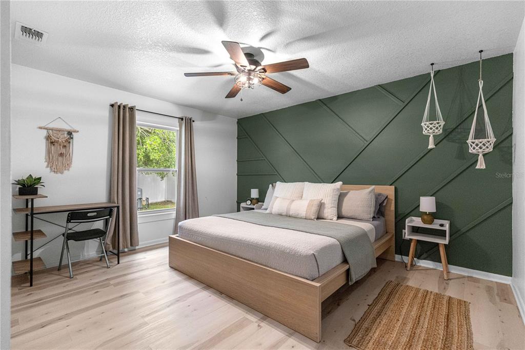 A bedroom features a green accent wall with geometric molding, a wooden bed, and desk — 431 NW 60TH AVENUE, OCALA, FL