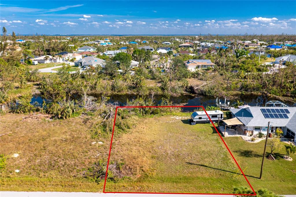 An aerial view shows a vacant residential lot outlined in red next to a house — 9582 SALT LAKE STREET, PORT CHARLOTTE, FL