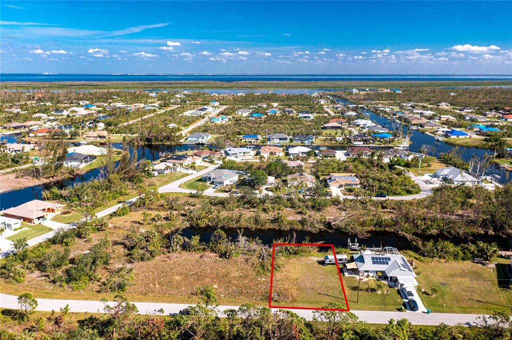 An aerial view shows a vacant residential lot outlined in red next to a house — 9582 SALT LAKE STREET, PORT CHARLOTTE, FL