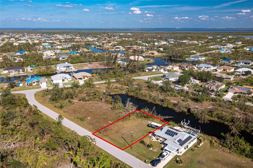 An aerial view shows a vacant rectangular lot outlined in red next to a waterfront house — 9582 SALT LAKE STREET, PORT CHARLOTTE, FL