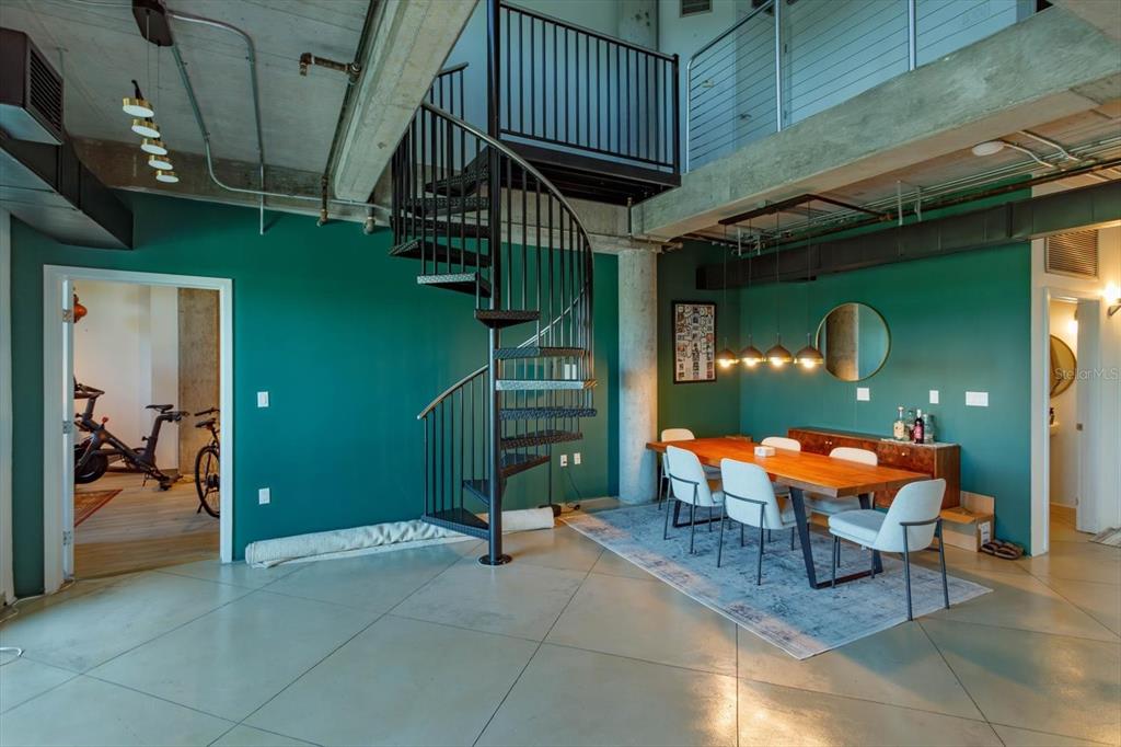 A dining area with a spiral staircase and teal walls in an industrial-style loft space — 10 N SUMMERLIN AVENUE UNIT 55, ORLANDO, FL