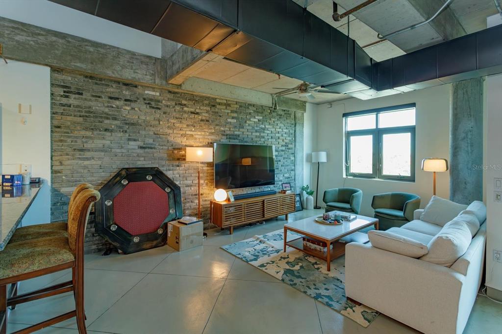 A living room features an exposed brick wall, concrete floors, and industrial-style ceiling ductwork — 10 N SUMMERLIN AVENUE UNIT 55, ORLANDO, FL