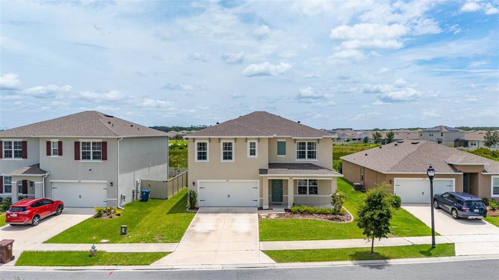 An exterior view of three suburban houses with driveways and lawns under a cloudy sky — 1273 RED HILL ROAD, DAVENPORT, FL