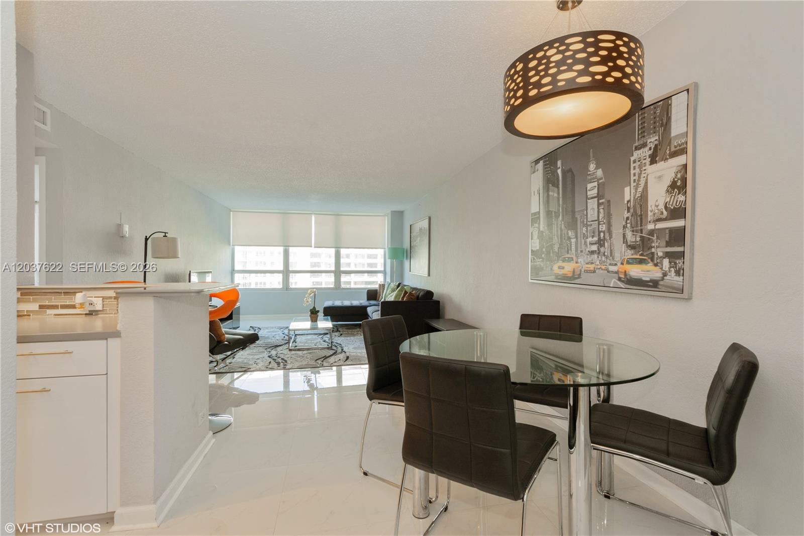 A dining area with a glass table and chairs sits adjacent to a living room — 1500 Bay Rd # 654S, Miami Beach FL 33139, MIAMI BEACH, FL