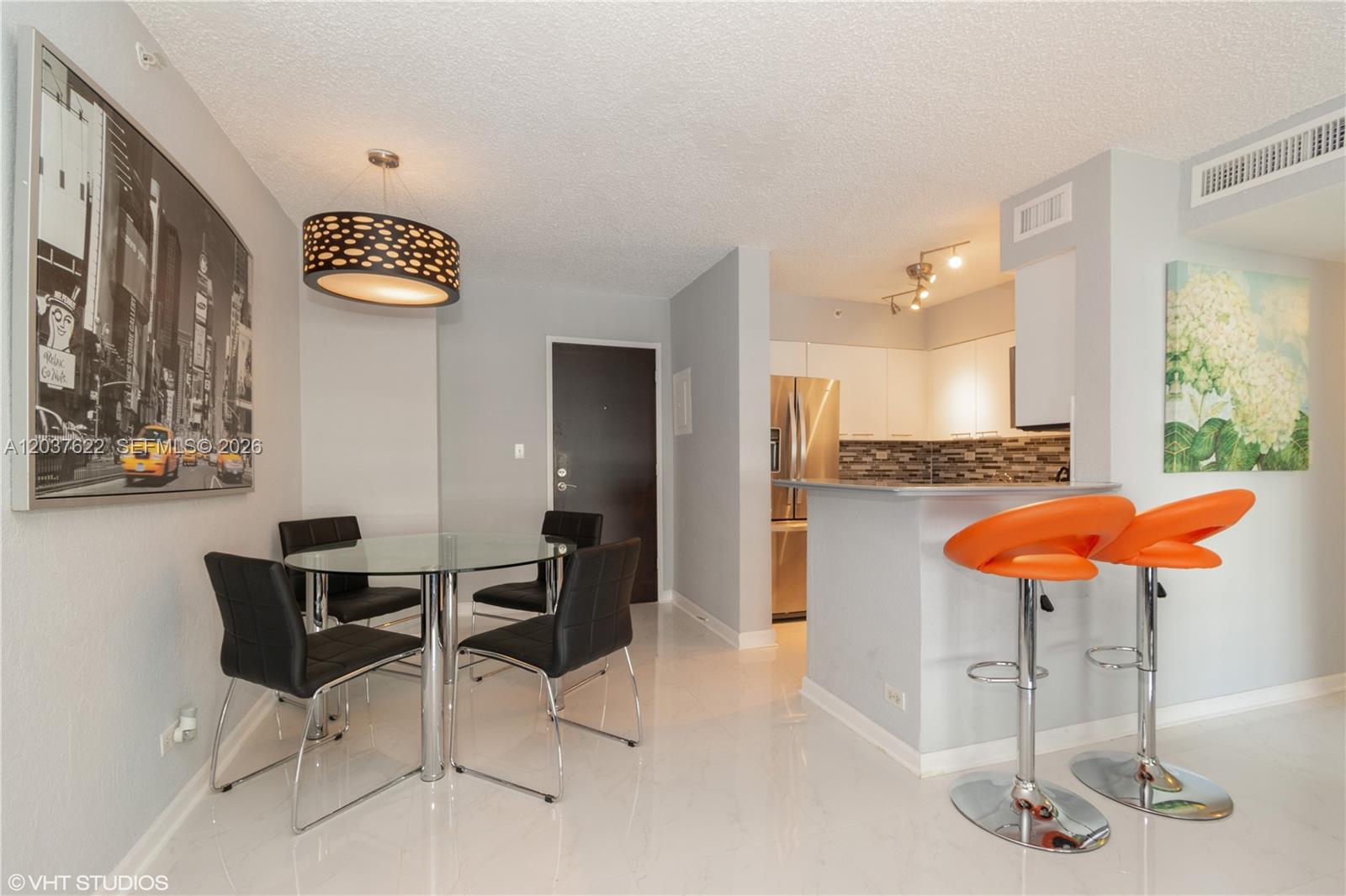 A dining area with a glass table and black chairs sits beside a kitchen counter — 1500 Bay Rd # 654S, Miami Beach FL 33139, MIAMI BEACH, FL