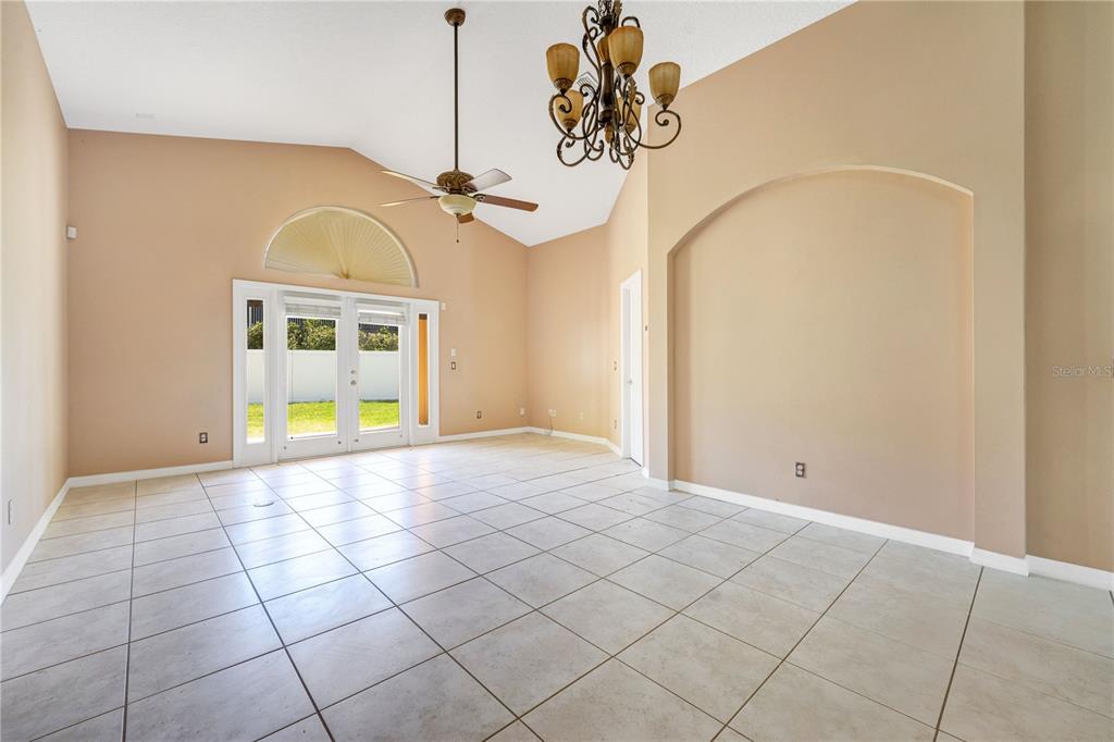 A living room features light-colored tile flooring, a vaulted ceiling, and a large arched alcove — 9720 NONACREST DRIVE, ORLANDO, FL