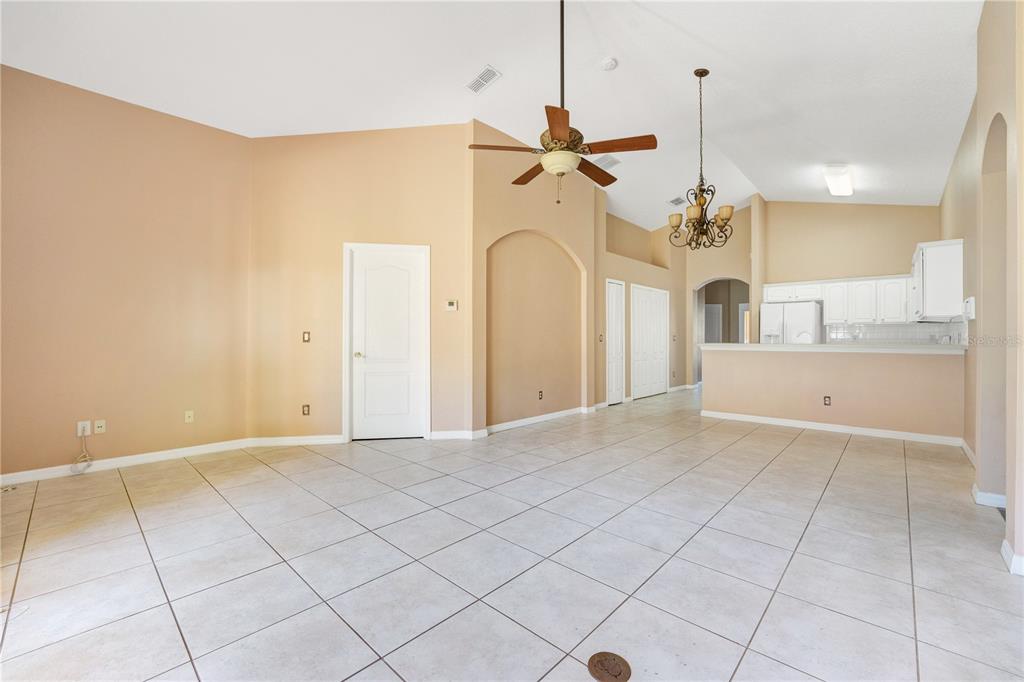 A spacious living area with beige walls, tile flooring, a ceiling fan, and an open kitchen — 9720 NONACREST DRIVE, ORLANDO, FL