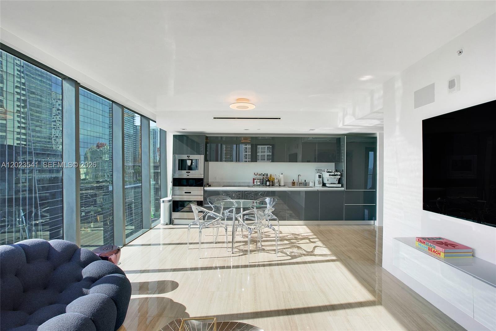 A modern open-concept kitchen and dining area features glossy gray cabinetry and floor-to-ceiling windows — 1451 Brickell Ave # 1604, Miami FL 33131, MIAMI, FL