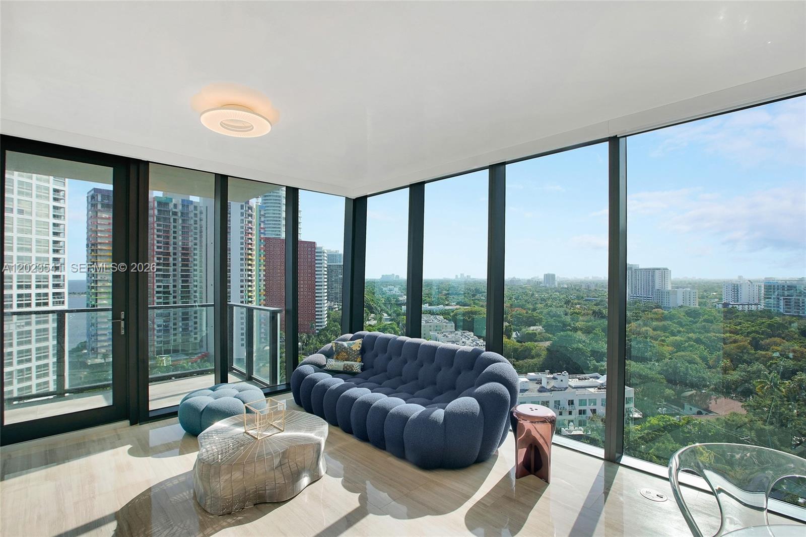 A living room features a blue tufted sofa, metallic coffee table, and floor-to-ceiling windows — 1451 Brickell Ave # 1604, Miami FL 33131, MIAMI, FL