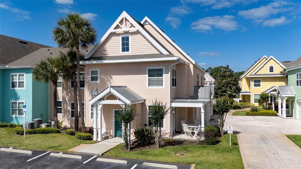 A peach-colored two-story building with a metal-roofed porch stands next to a parking lot — 3002 LIMBO LANE UNIT 101, KISSIMMEE, FL
