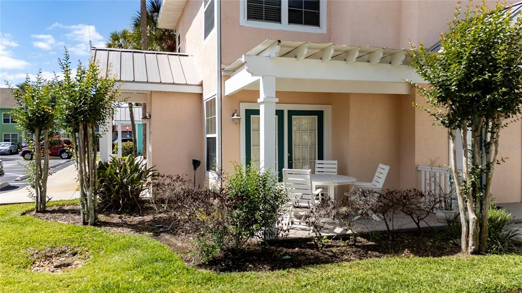 A peach-colored house exterior features a covered patio with white furniture and landscaping — 3002 LIMBO LANE UNIT 101, KISSIMMEE, FL