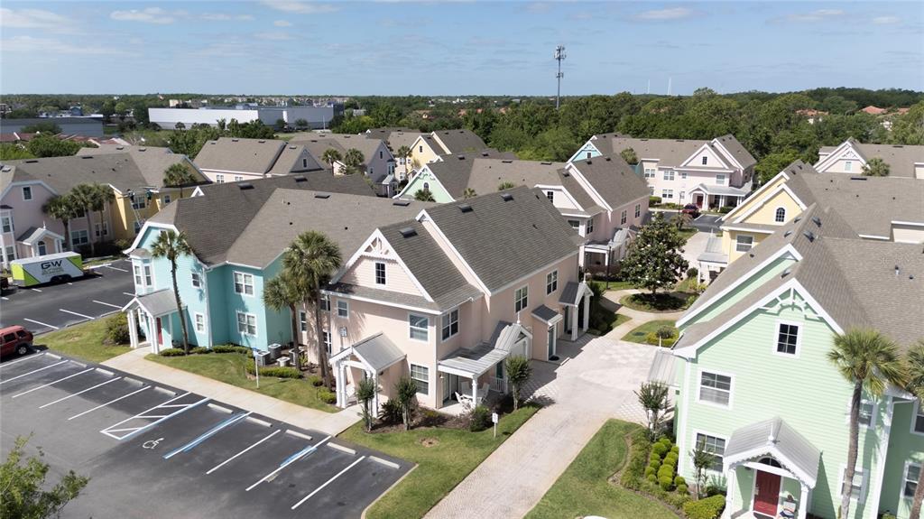 An aerial view shows several pastel-colored multi-story townhouses with parking spaces and palm trees — 3002 LIMBO LANE UNIT 101, KISSIMMEE, FL