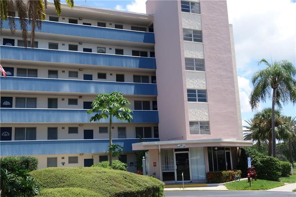 A multi-story apartment building features blue balconies, a pink stairwell tower, and landscaped grounds — 200 N BETTY LANE UNIT 2E, CLEARWATER, FL