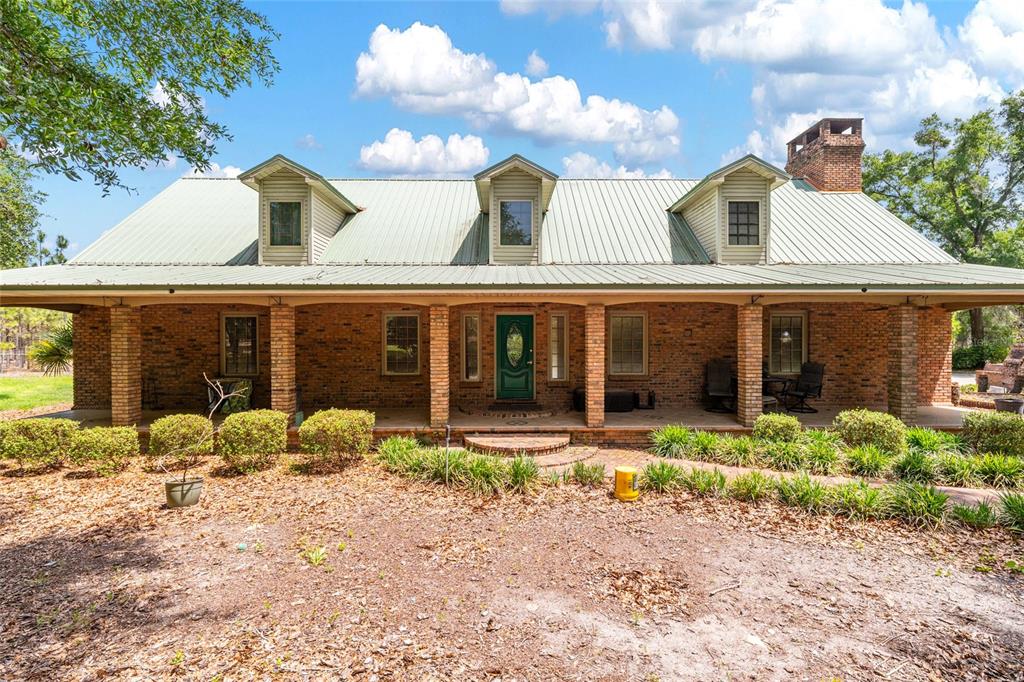 A single-story brick house with a metal roof, dormer windows, and a wide front porch — 272 NE COUNTY ROAD 337, TRENTON, FL