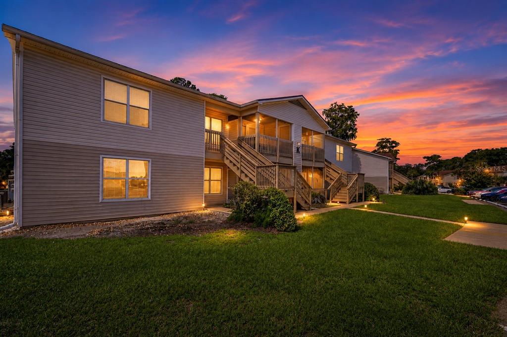 Exterior view of a two-story apartment building with wooden staircases at sunset — 1600 BIG TREE ROAD UNIT K1, DAYTONA BEACH, FL