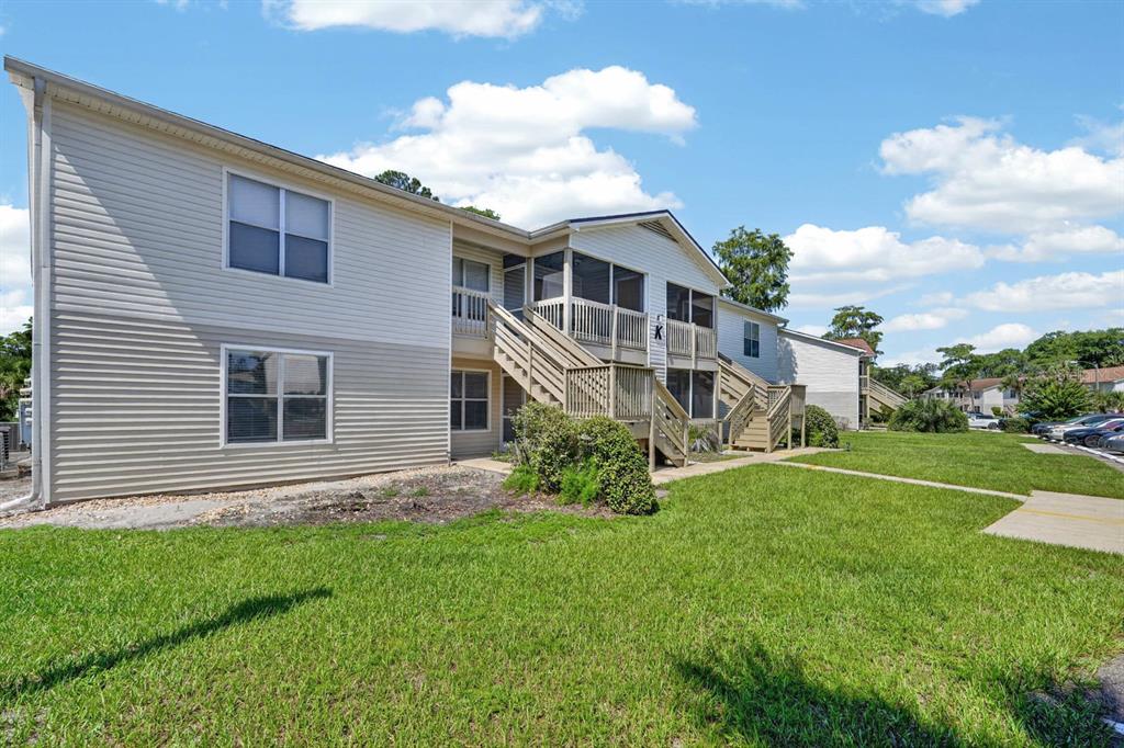 A two-story apartment building with beige siding, wooden staircases, and screened-in balconies — 1600 BIG TREE ROAD UNIT K1, DAYTONA BEACH, FL