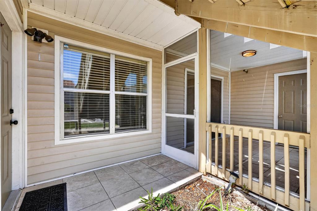 A tiled entryway leads to a screened-in porch with a wooden railing and beige siding — 1600 BIG TREE ROAD UNIT K1, DAYTONA BEACH, FL