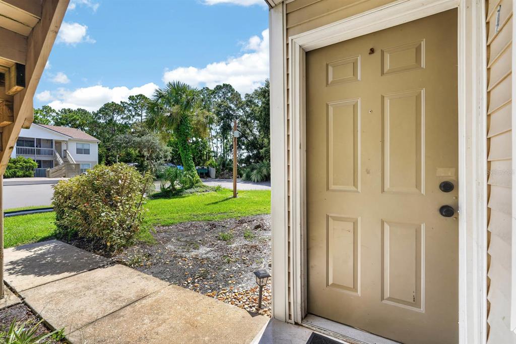 A beige six-panel door opens onto a concrete patio overlooking a grassy outdoor area — 1600 BIG TREE ROAD UNIT K1, DAYTONA BEACH, FL