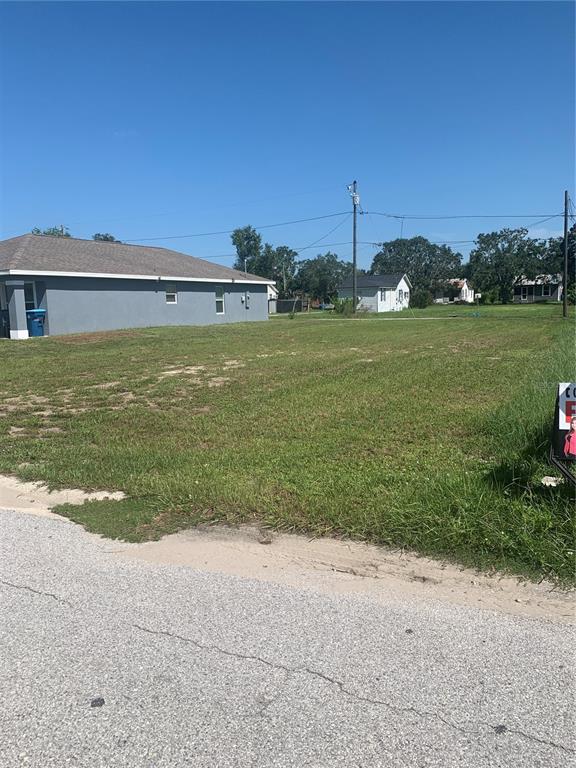 A vacant, grassy residential lot sits next to a gray house under a clear sky — 517 LINCOLN AVENUE W, LAKE WALES, FL