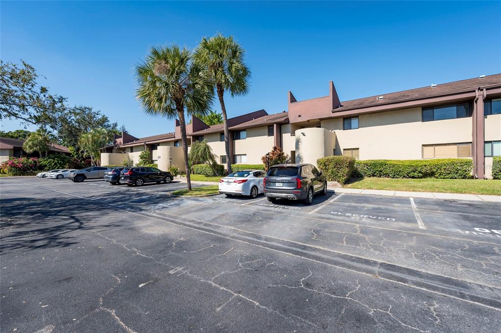 A multi-story apartment building with a parking lot in the foreground and palm trees — 735 S VILLAGE DRIVE N UNIT 206, ST PETERSBURG, FL