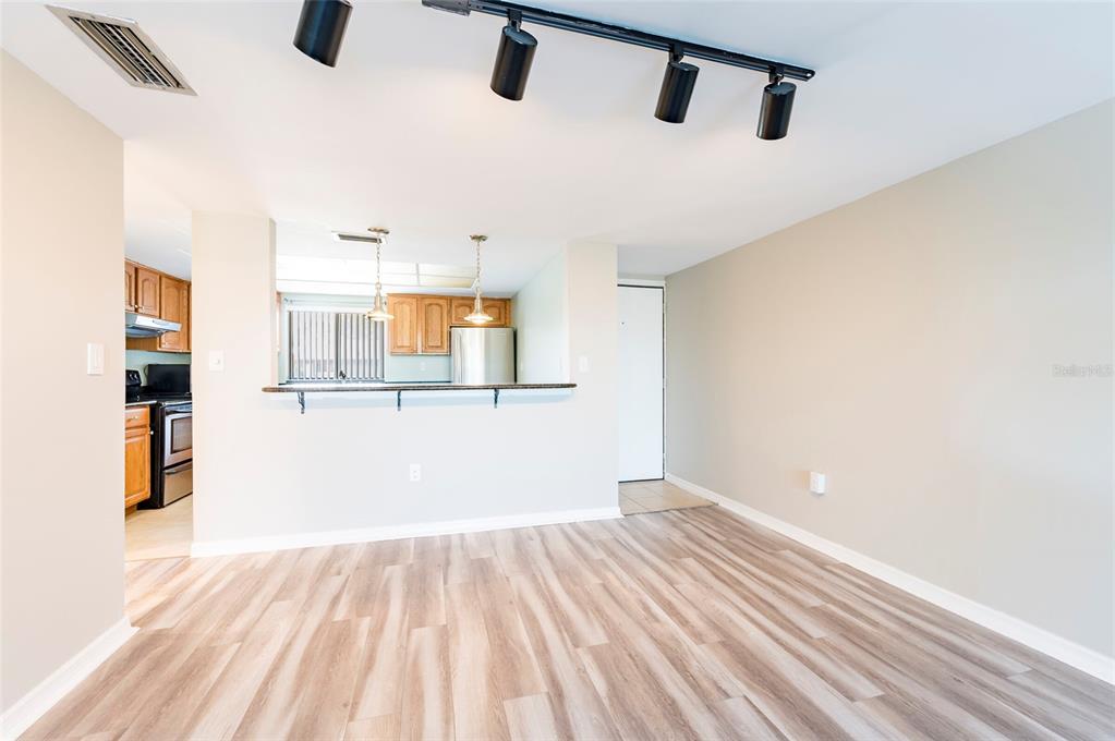 A living area with wood-look flooring, track lighting, and a breakfast bar overlooking the kitchen — 735 S VILLAGE DRIVE N UNIT 206, ST PETERSBURG, FL