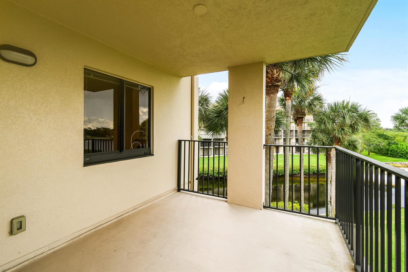 A covered balcony with a concrete floor, black metal railings, and a view of palm trees — 1701 Marina Isle Way # 301, Jupiter FL 33477, JUPITER, FL