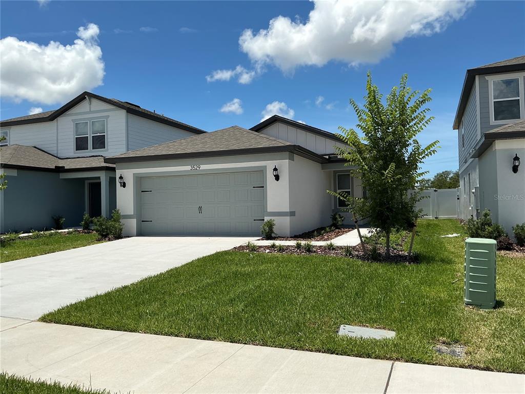 A single-story suburban house with a gray garage, white siding, and a green utility box — 3529 HORNBEAM ROAD, SPRING HILL, FL