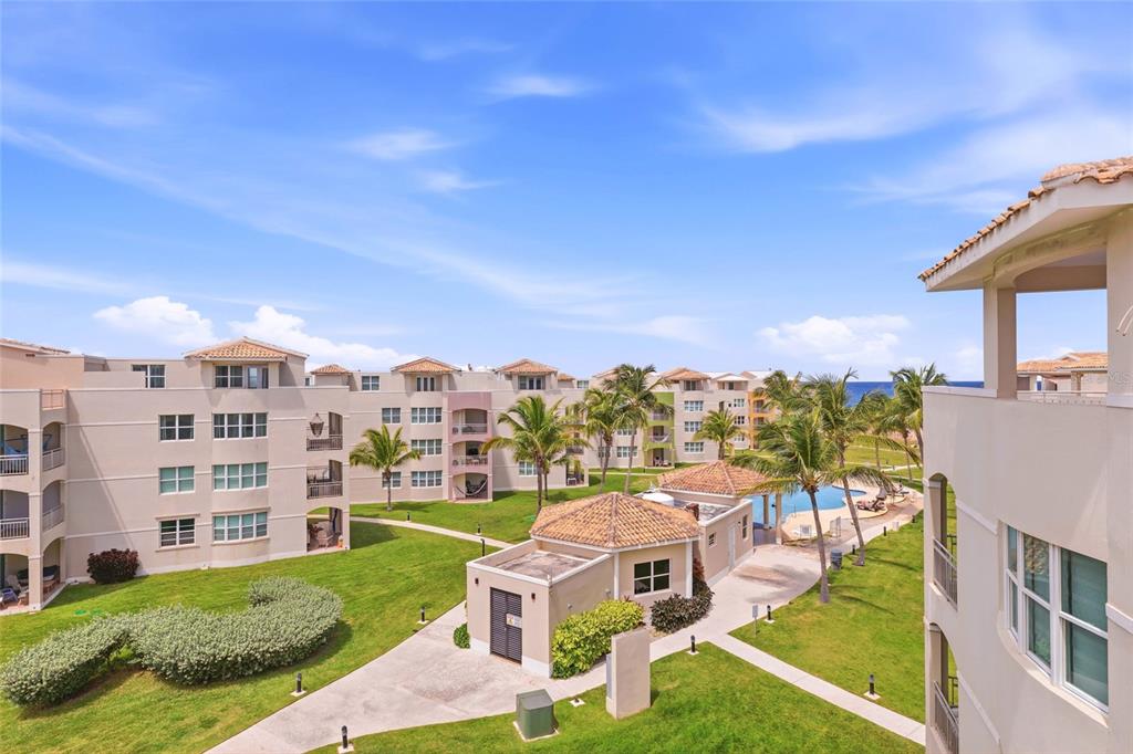 An exterior view of a multi-story apartment complex with a central pool and palm trees — Haudimar Beach Apartments PH UNIT G303, ISABELA, PR