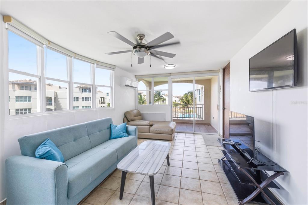 A living room features a blue sofa, a coffee table, a television, and a balcony — Haudimar Beach Apartments PH UNIT G303, ISABELA, PR