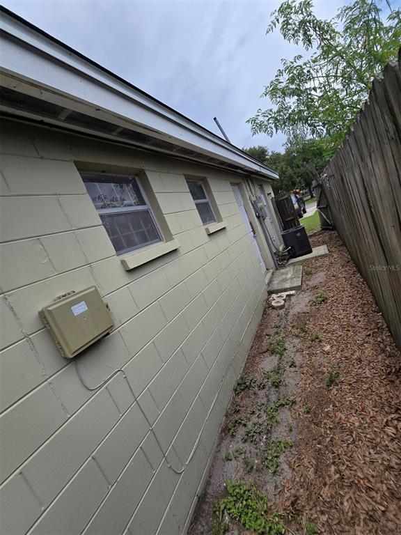 The exterior side of a concrete block house features two windows, a utility box, and fencing — 4426 13TH AVENUE S, ST PETERSBURG, FL