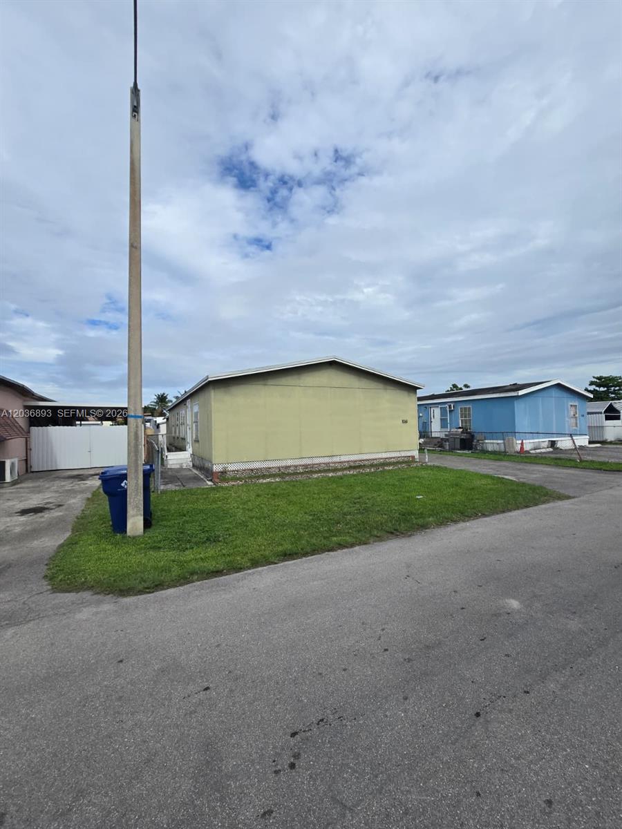 A light green mobile home sits on a grassy lot next to a blue house — 1061 SW 131 PL, Miami FL 33184, MIAMI, FL