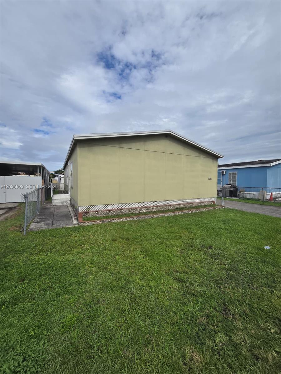 A light green mobile home sits on a grassy lot under a cloudy sky — 1061 SW 131 PL, Miami FL 33184, MIAMI, FL