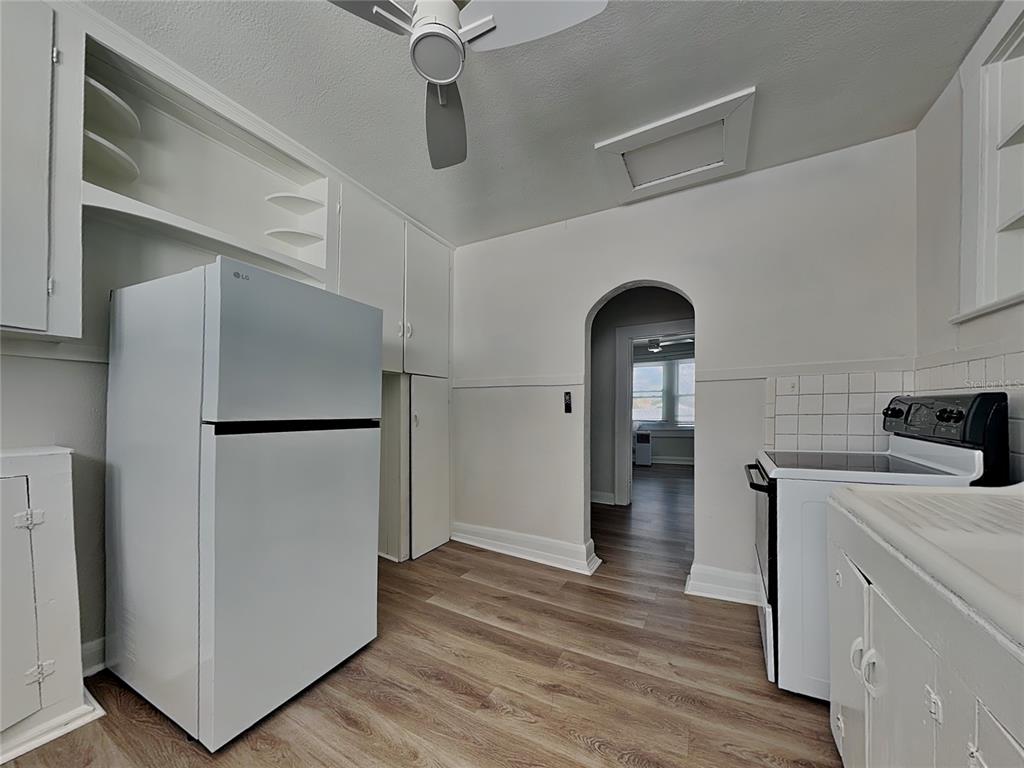 A kitchen features white appliances, wood-look flooring, and an arched doorway leading to another room — 2904 W CHESTNUT STREET UNIT 2, TAMPA, FL