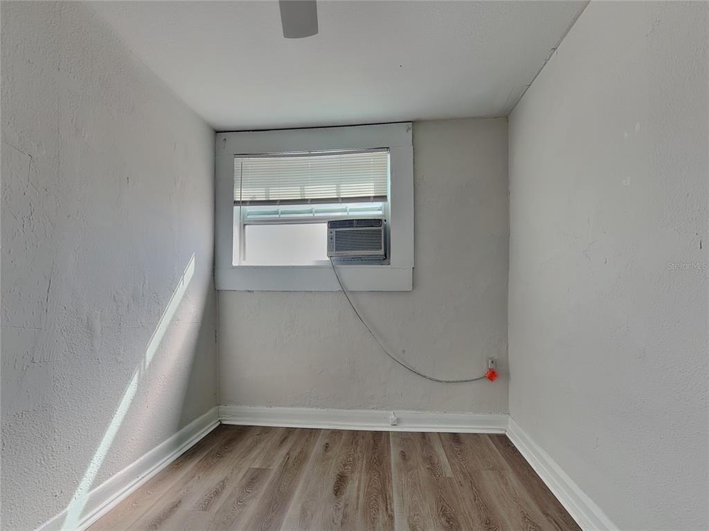 A small, empty room with light gray walls, wood-look flooring, and a window air conditioner — 2904 W CHESTNUT STREET UNIT 2, TAMPA, FL