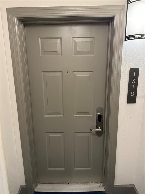 A gray six-panel door with a digital lock and a vertical unit number sign — 14501 GROVE RESORT AVENUE UNIT 1318, WINTER GARDEN, FL