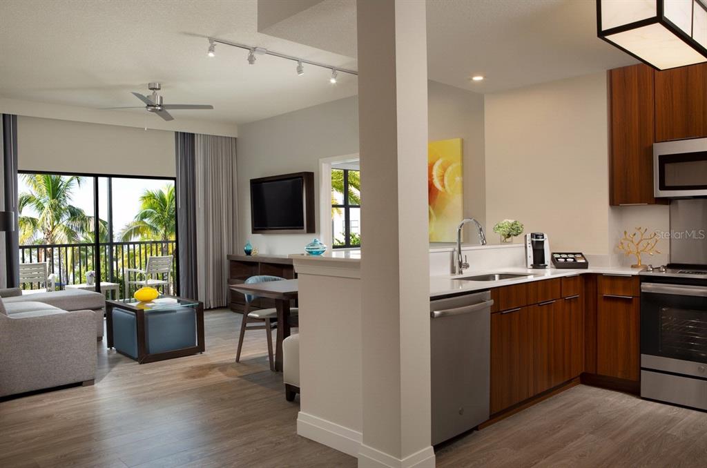 An open-concept kitchen and living area with wood-look flooring, stainless steel appliances, and balcony access — 14501 GROVE RESORT AVENUE UNIT 1318, WINTER GARDEN, FL