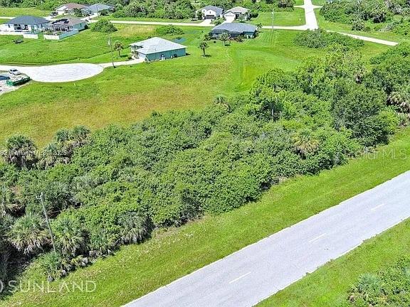 An aerial view shows a vacant, heavily wooded lot adjacent to a paved road — 316 SUNSET ROAD, ROTONDA WEST, FL