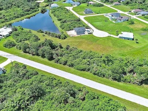 This aerial view shows a residential neighborhood with a pond and undeveloped land — 316 SUNSET ROAD, ROTONDA WEST, FL