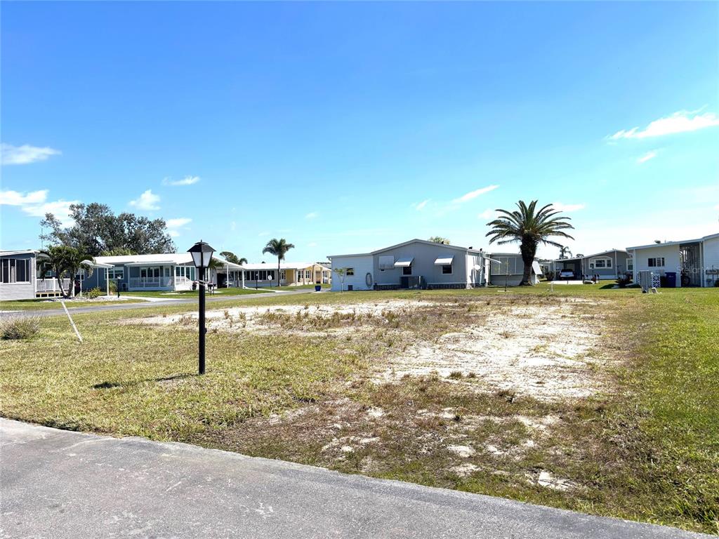 A vacant, sandy lot sits in a residential neighborhood with mobile homes and palm trees — 502 SAN CLEMENTE CIRCLE, NORTH PORT, FL