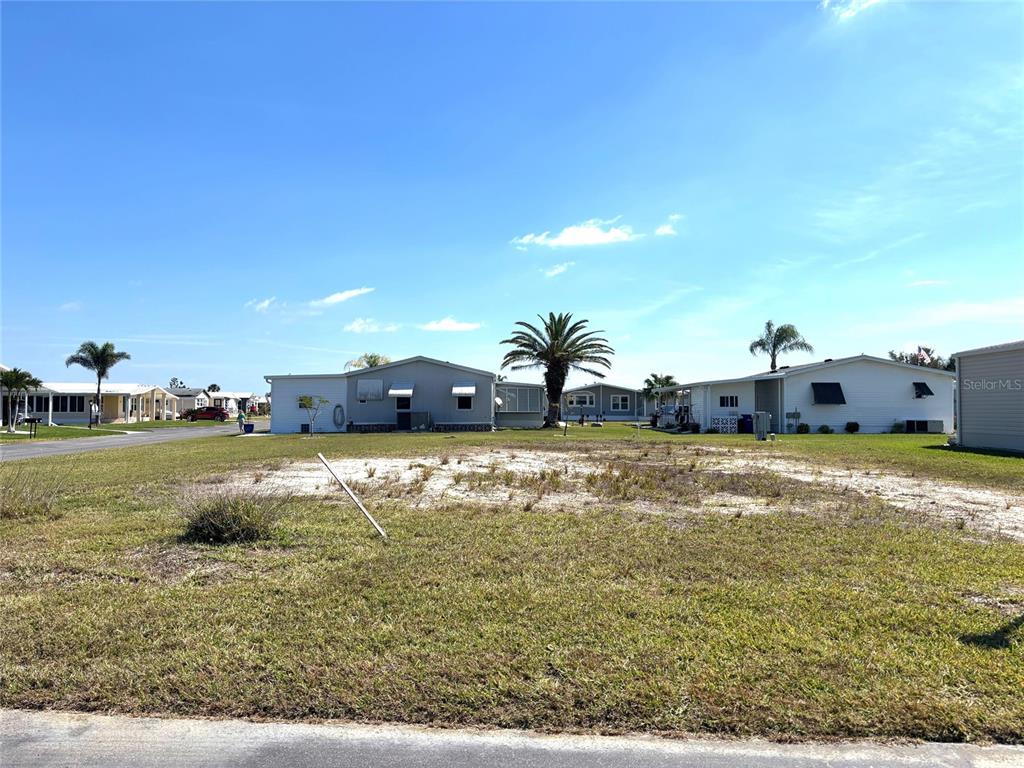A vacant, sandy lot sits in front of several manufactured homes under a clear sky — 502 SAN CLEMENTE CIRCLE, NORTH PORT, FL