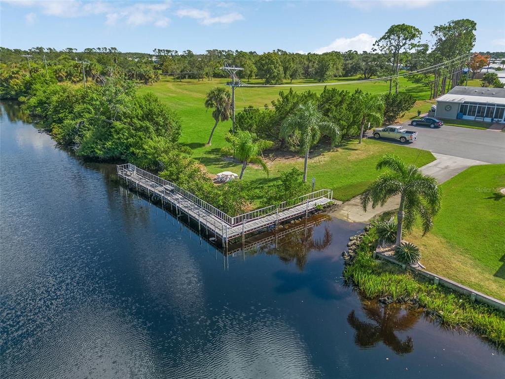 An aerial view shows a wooden dock extending into a canal beside a grassy yard — 502 SAN CLEMENTE CIRCLE, NORTH PORT, FL