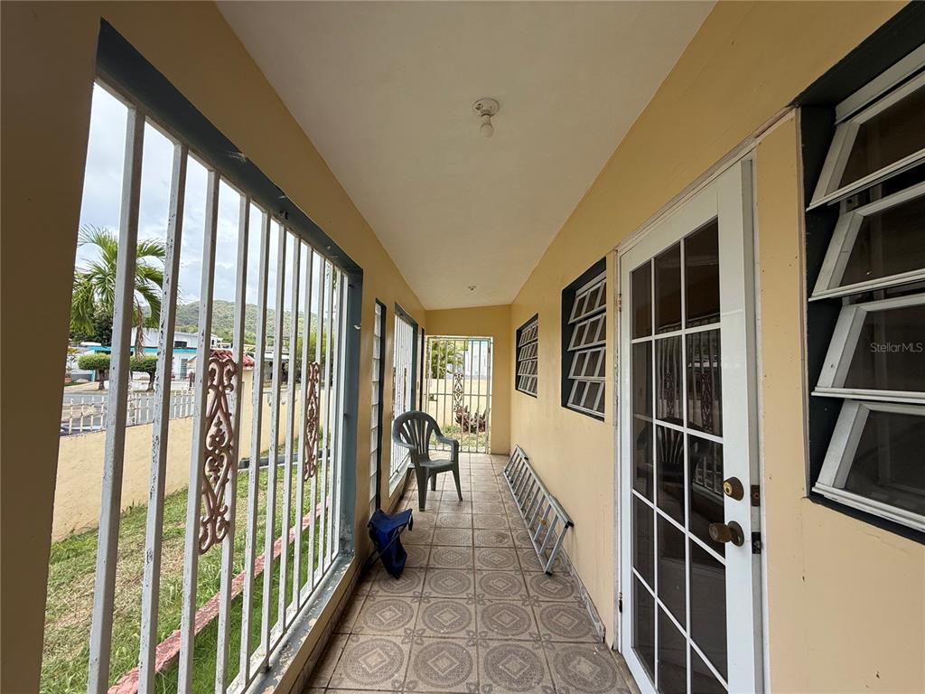 A covered porch with tiled flooring, metal security bars, and a glass-paned door — 20 ST VILLA NUEVA UNIT W-41, CAGUAS, PR