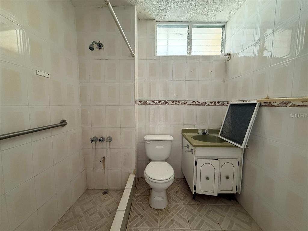 A bathroom features tiled walls, a walk-in shower area, a toilet, and a vanity cabinet — 20 ST VILLA NUEVA UNIT W-41, CAGUAS, PR
