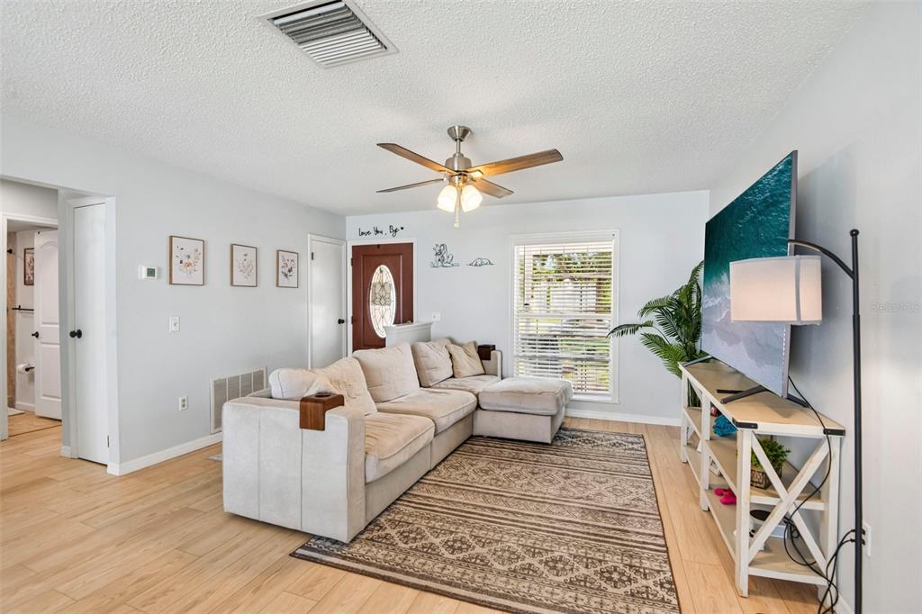 A living room features a beige sectional sofa, a patterned area rug, and a television console — 11033 SALT TREE DRIVE, PORT RICHEY, FL