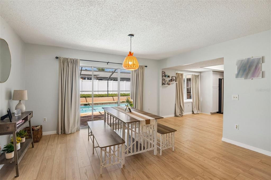 A dining area with a wooden table, benches, and a sliding door leading to a pool — 11033 SALT TREE DRIVE, PORT RICHEY, FL
