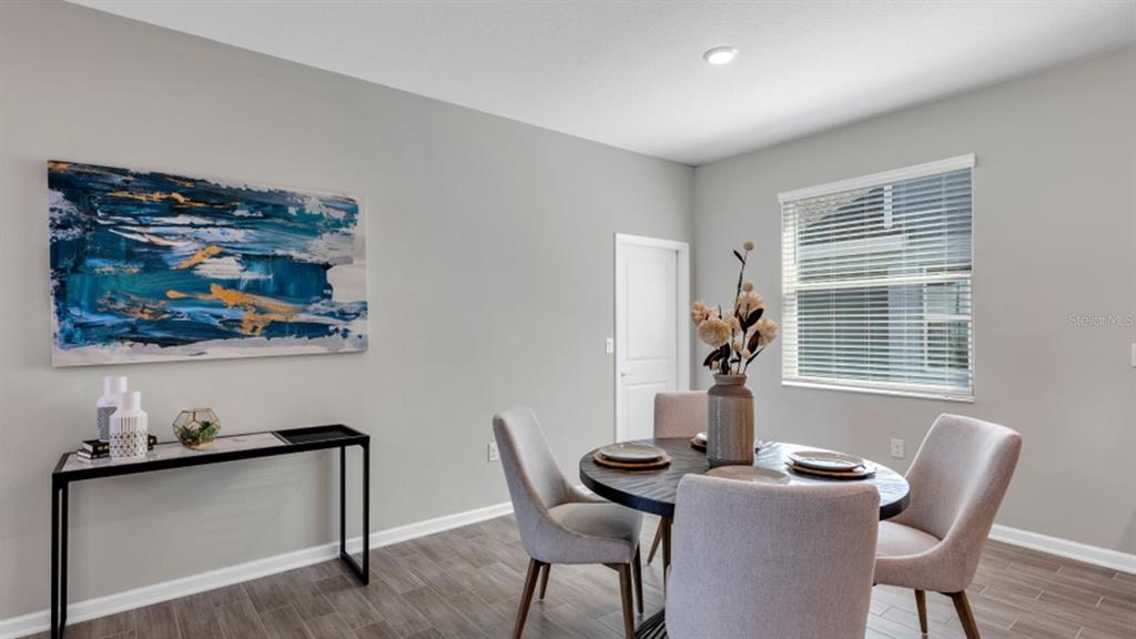 A dining room features a round table, four upholstered chairs, a console table, and artwork — 5594 RONIN DRIVE, ST CLOUD, FL