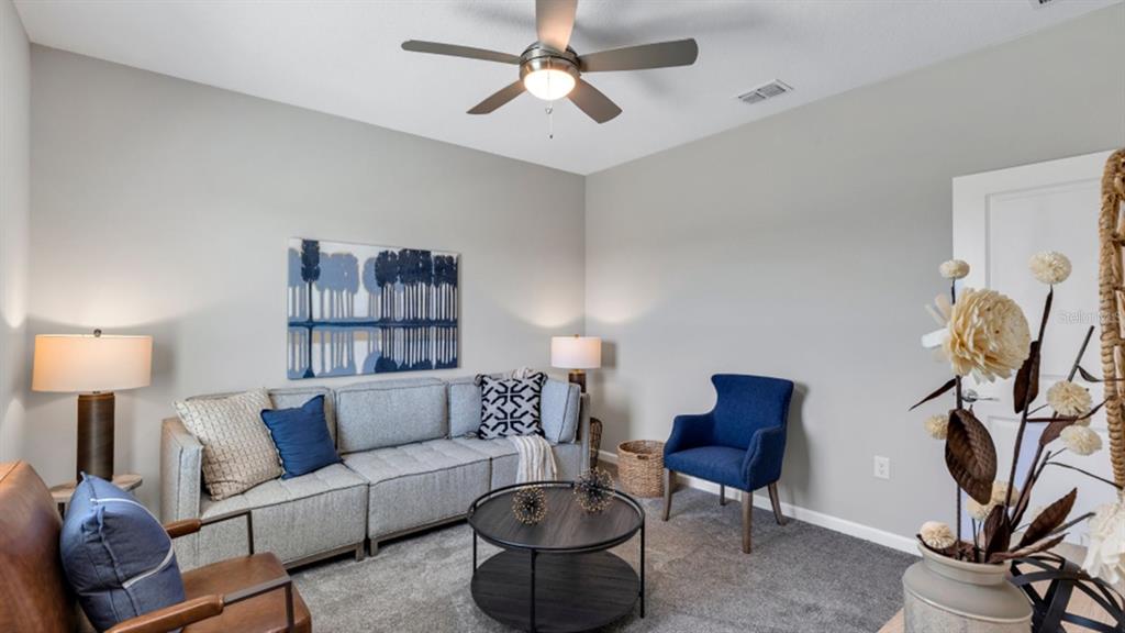 A living room features a gray sectional sofa, a blue armchair, and a round coffee table — 5594 RONIN DRIVE, ST CLOUD, FL